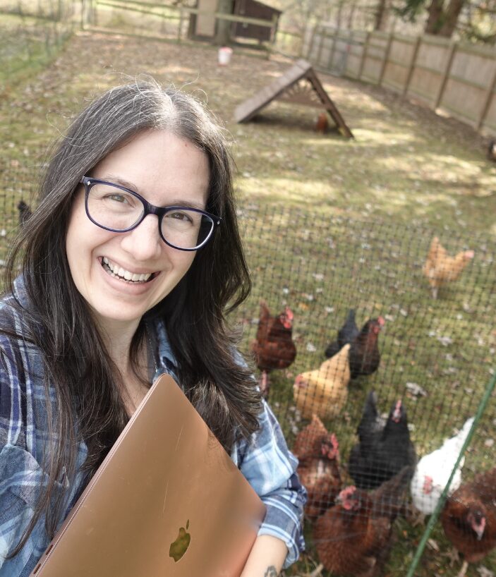 Cozy mystery Developmental editor Rachel Clair holding a laptop with her chickens in the background